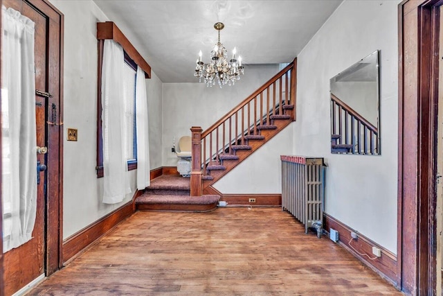 entryway with an inviting chandelier and wood-type flooring