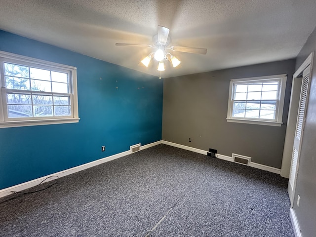 carpeted spare room with ceiling fan and a textured ceiling