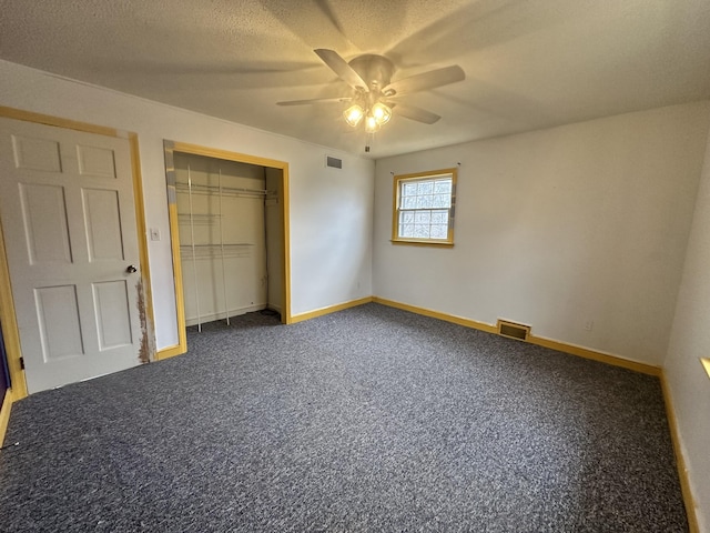 unfurnished bedroom featuring a textured ceiling, ceiling fan, a closet, and dark carpet