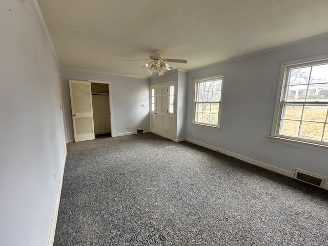 unfurnished room with ceiling fan, ornamental molding, and dark colored carpet