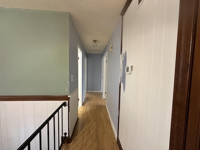 corridor with a textured ceiling and hardwood / wood-style floors