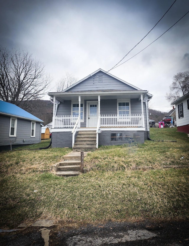 bungalow-style home with covered porch, stairway, and a front lawn