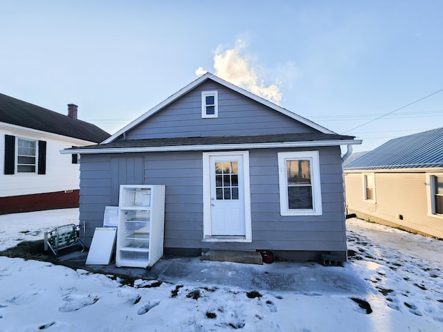 snow covered house with roof with shingles