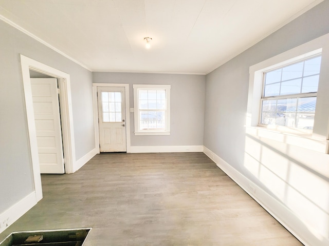 interior space with ornamental molding, light wood-type flooring, and baseboards