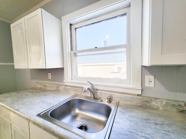 kitchen featuring white cabinets, light countertops, and a sink