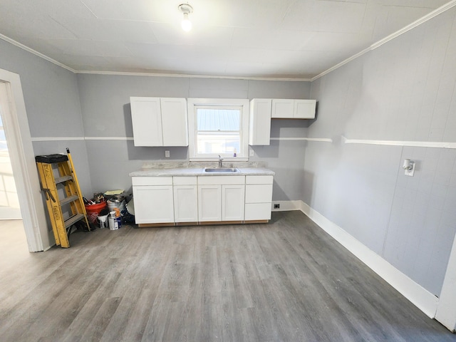 kitchen featuring light wood finished floors, white cabinetry, a sink, and ornamental molding