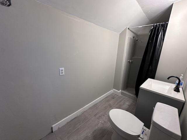 bathroom with hardwood / wood-style floors, lofted ceiling, vanity, toilet, and a shower with shower curtain