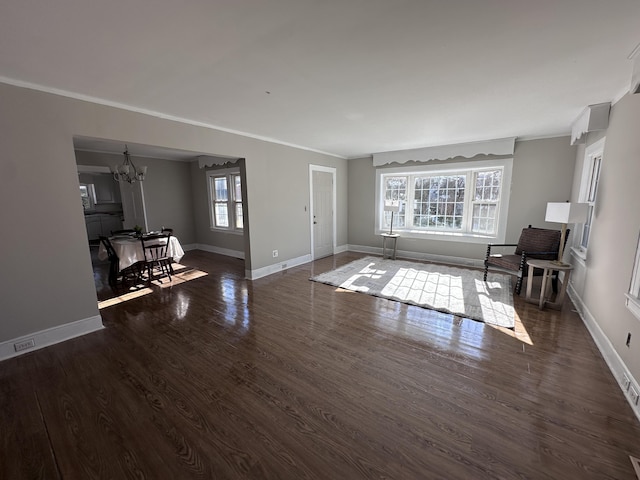 living room featuring crown molding, dark wood-type flooring, and an inviting chandelier