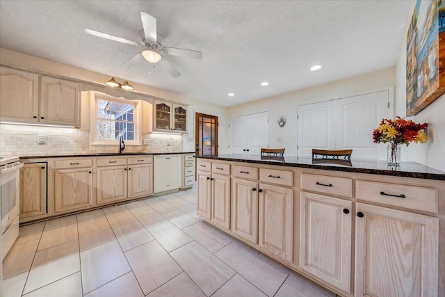 kitchen featuring sink, backsplash, dishwasher, and dark stone countertops