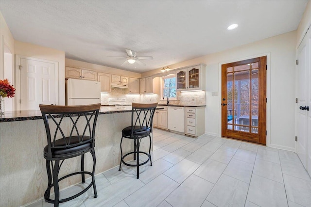 kitchen with white appliances, tasteful backsplash, a kitchen breakfast bar, sink, and kitchen peninsula