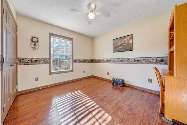 interior space with ceiling fan, a textured ceiling, hardwood / wood-style flooring, and built in desk