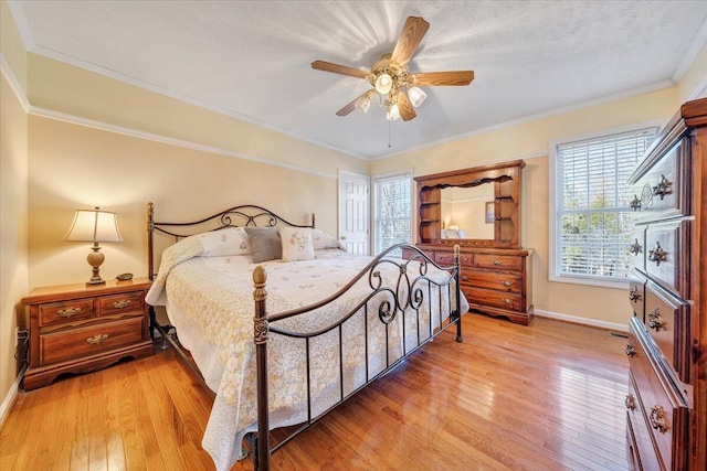 bedroom with ceiling fan, ornamental molding, light hardwood / wood-style floors, and a textured ceiling