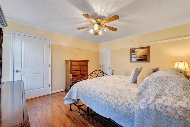 bedroom with ceiling fan, ornamental molding, hardwood / wood-style floors, and a textured ceiling