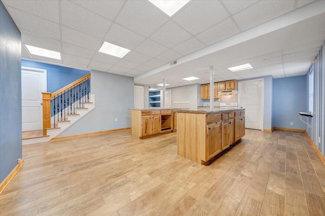 kitchen with light stone countertops, a kitchen island, pendant lighting, and a drop ceiling