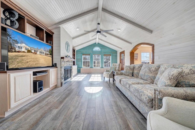 living room with a fireplace, wooden ceiling, hardwood / wood-style flooring, vaulted ceiling with beams, and wood walls