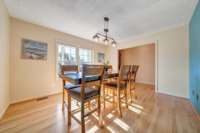 dining area with light hardwood / wood-style floors and a textured ceiling