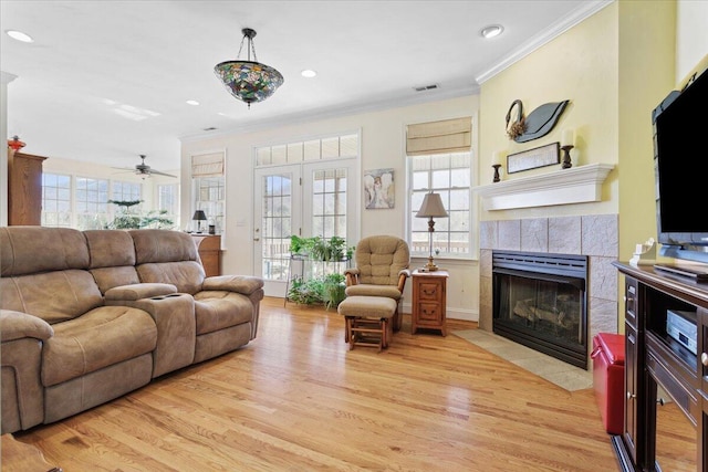 living room with crown molding, a fireplace, and light hardwood / wood-style flooring