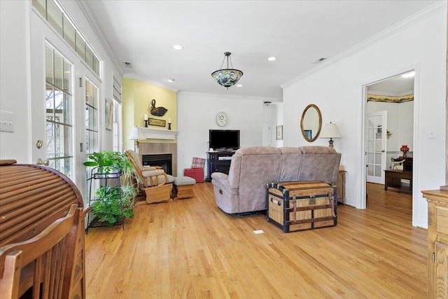 living room with a tile fireplace, crown molding, and light hardwood / wood-style floors