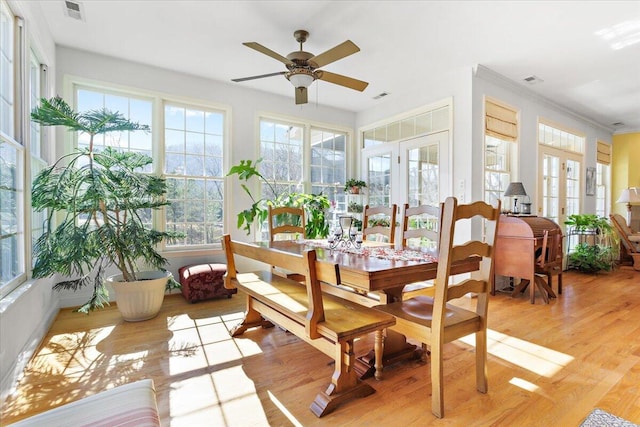 sunroom / solarium featuring a healthy amount of sunlight, ceiling fan, and french doors