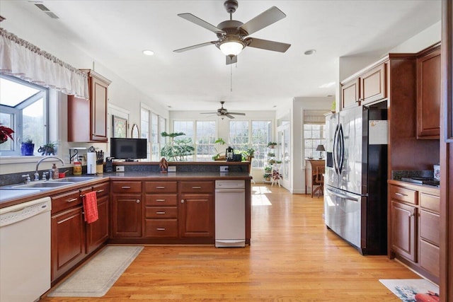 kitchen with sink, dishwasher, stainless steel refrigerator with ice dispenser, light hardwood / wood-style floors, and kitchen peninsula