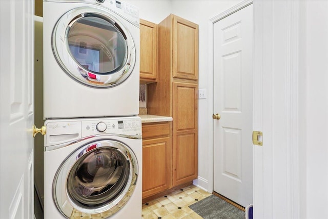 clothes washing area with cabinets and stacked washer and clothes dryer