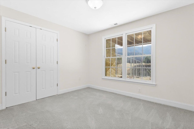 unfurnished bedroom featuring light carpet and a closet