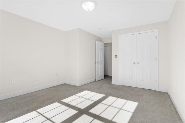 unfurnished bedroom with light colored carpet and a closet