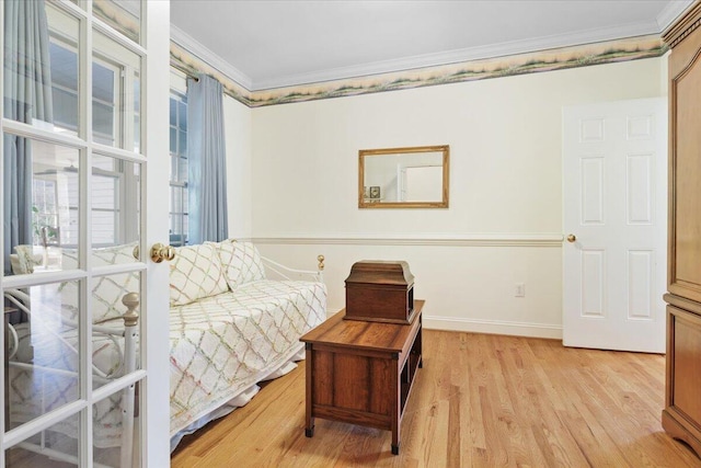 bedroom featuring crown molding, light hardwood / wood-style floors, and french doors