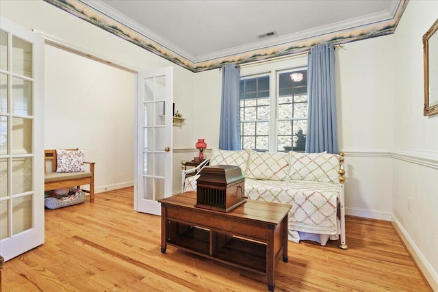 sitting room featuring crown molding, light wood-type flooring, and french doors