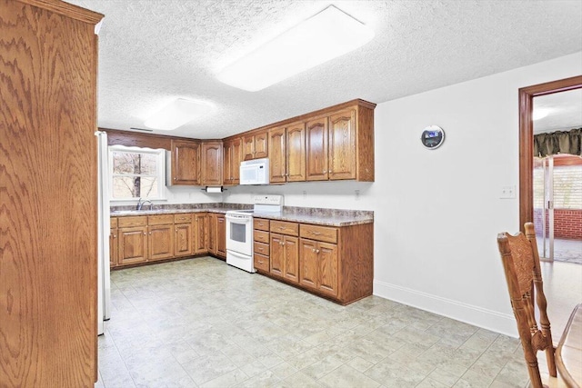 kitchen with sink, white appliances, and a textured ceiling