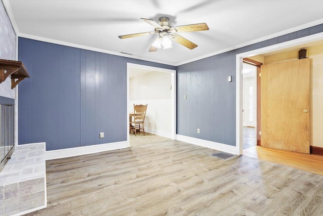 unfurnished room with ornamental molding, ceiling fan, light wood-type flooring, and a fireplace