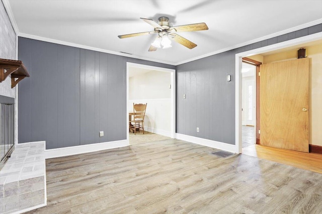 unfurnished living room featuring baseboards, visible vents, ceiling fan, ornamental molding, and wood finished floors