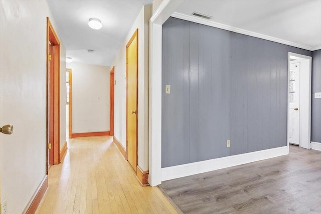 hall featuring wood finished floors, visible vents, and baseboards