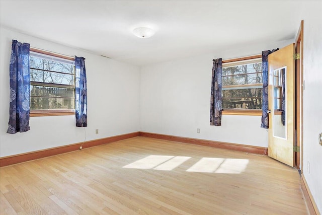 spare room with baseboards, light wood-style floors, and a healthy amount of sunlight