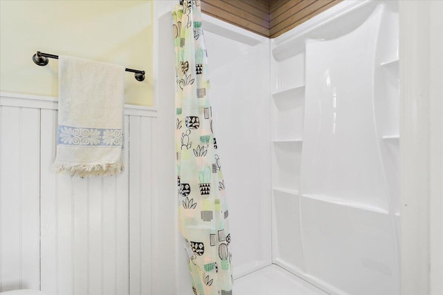 full bathroom featuring a wainscoted wall and a shower with curtain