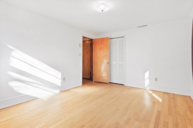 spare room featuring wood-type flooring and baseboards