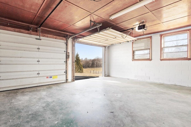 garage featuring concrete block wall and a garage door opener