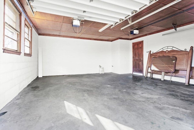 garage featuring concrete block wall and a garage door opener