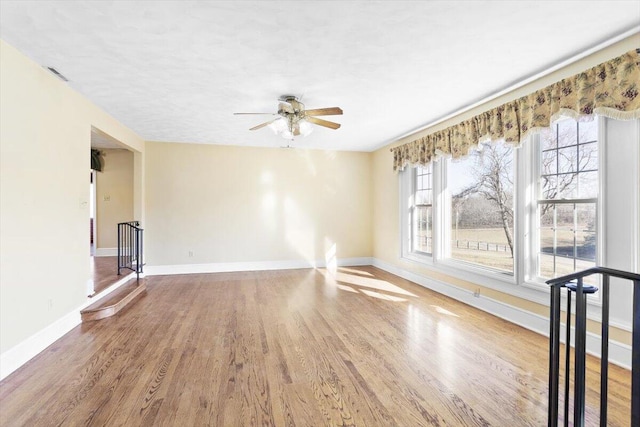 unfurnished room with a ceiling fan, baseboards, visible vents, and wood finished floors