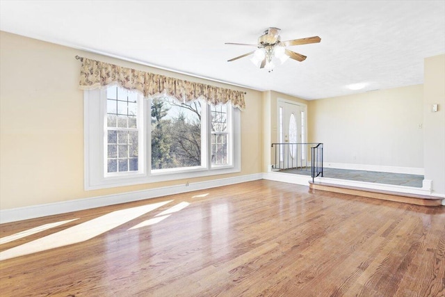 unfurnished room featuring a ceiling fan, baseboards, and wood finished floors