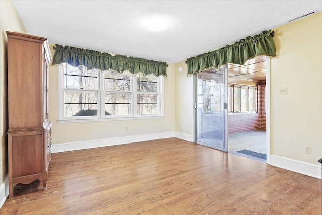 unfurnished dining area featuring baseboards, visible vents, and wood finished floors