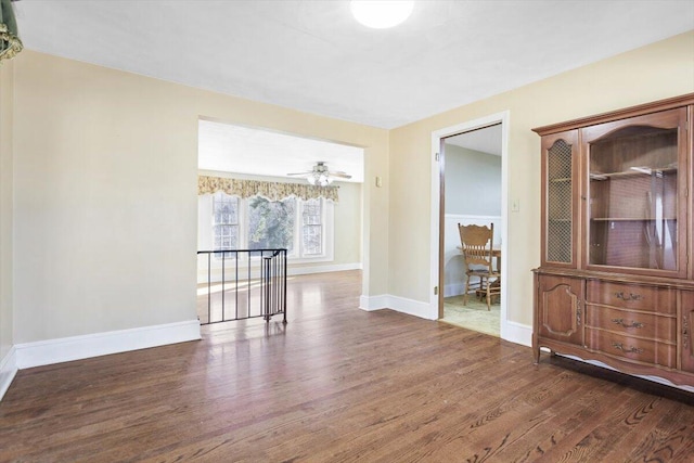 unfurnished room with ceiling fan, wood finished floors, and baseboards