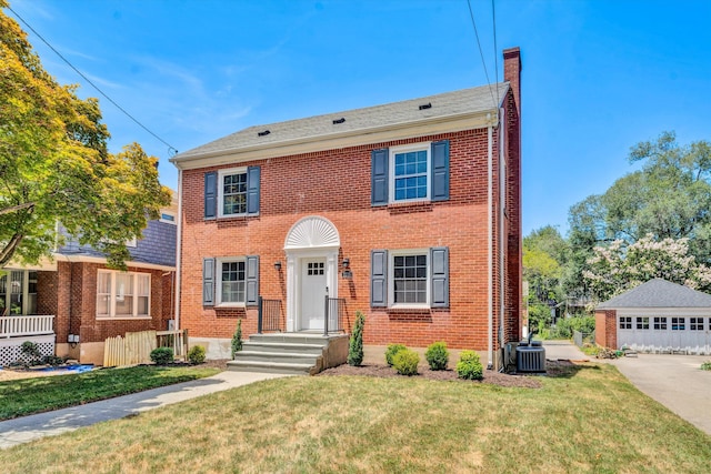 colonial home featuring a garage, an outdoor structure, cooling unit, and a front yard