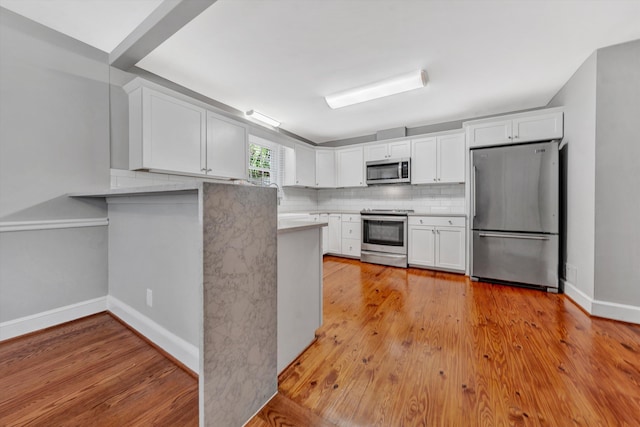 kitchen featuring stainless steel appliances, kitchen peninsula, and white cabinets