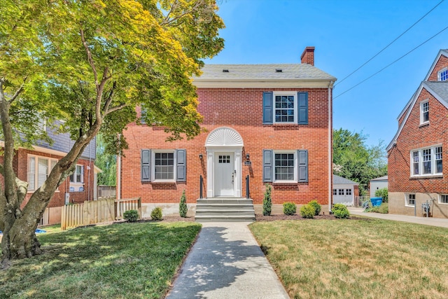 colonial-style house with a garage, an outdoor structure, and a front lawn