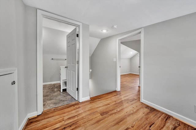 hall featuring lofted ceiling and light hardwood / wood-style flooring