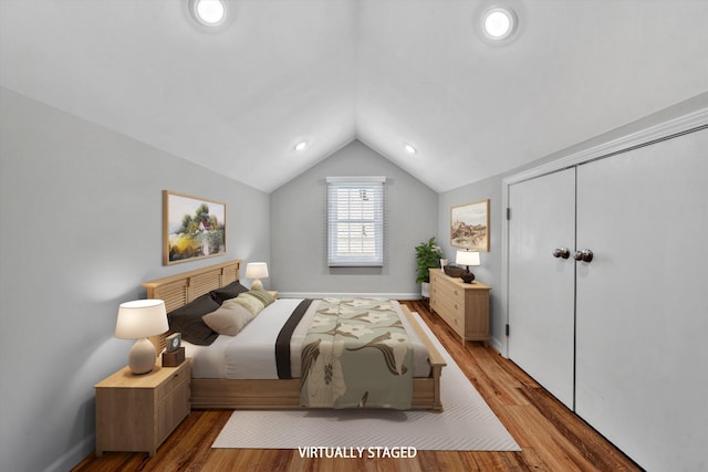 bedroom featuring hardwood / wood-style flooring, lofted ceiling, and a closet