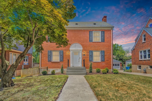 colonial-style house with an outbuilding, a garage, and a lawn