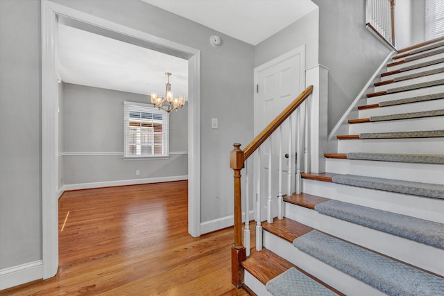 staircase featuring hardwood / wood-style floors and a chandelier