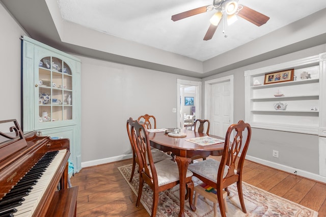 dining area featuring dark wood-type flooring, ceiling fan, and built in shelves